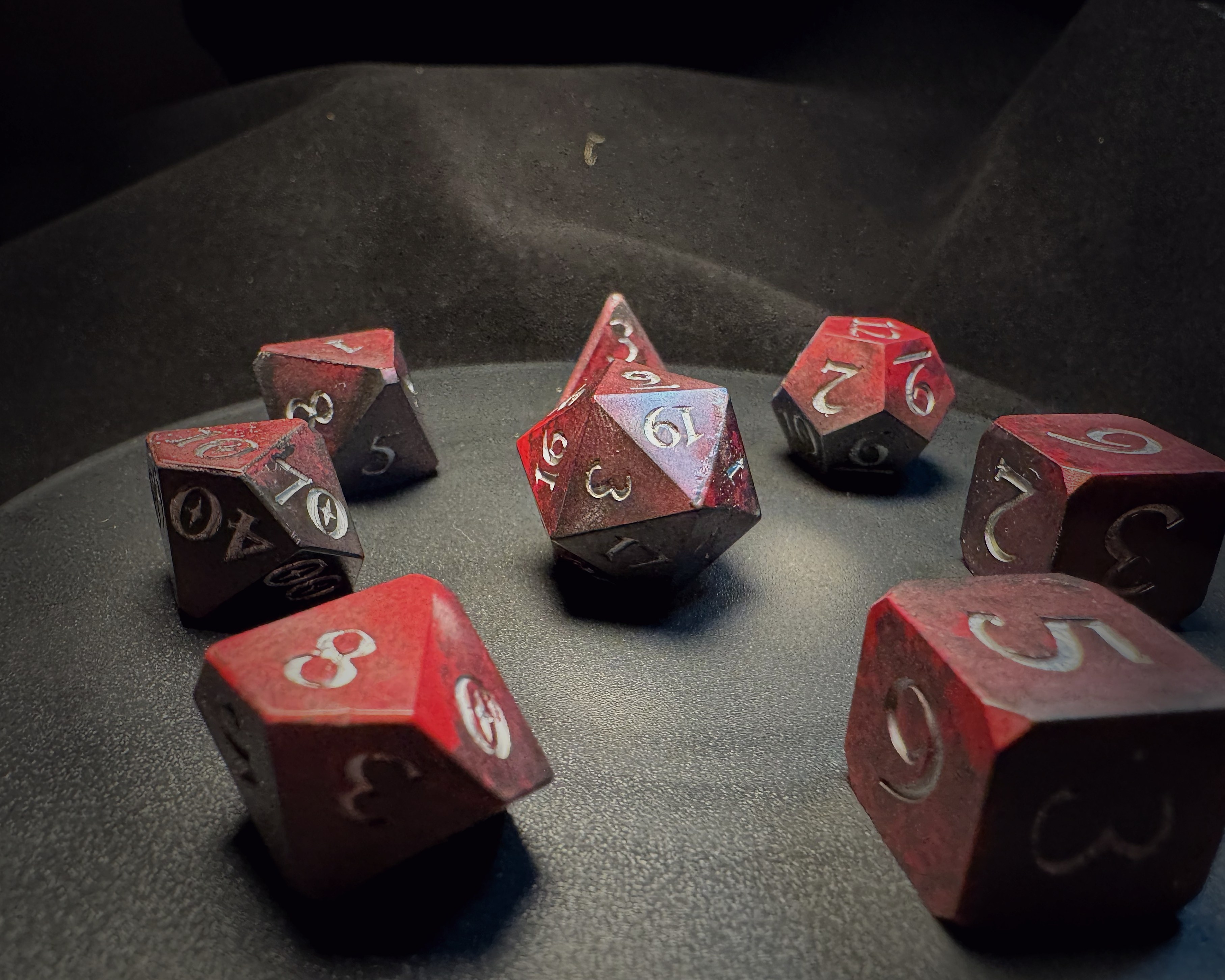 Full set of red composite dice arranged in a circle on dark velvet surface
